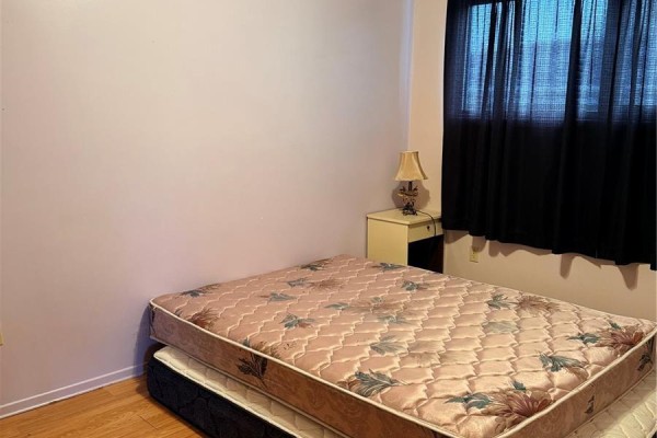 Bedroom with a mattress on the floor, a nightstand with a lamp, and a dark curtained window. - 512 Mcnab Street, Burstall
