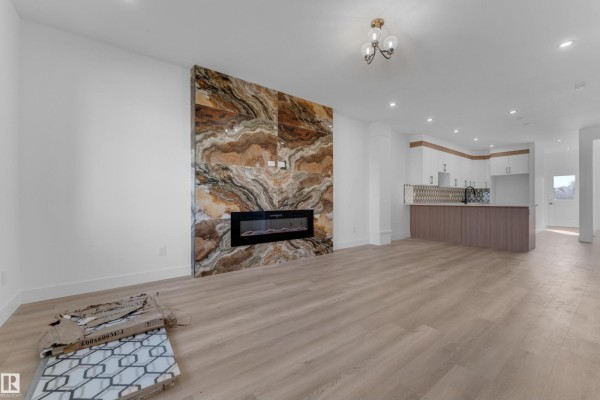 Living room featuring a modern electric fireplace with a striking marble surround. - 512 Robinson Bv, Leduc