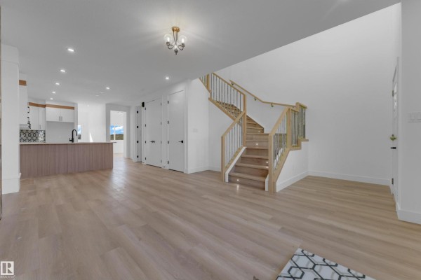 Open-concept living space with a fireplace, leading to a kitchen with an island. - 512 Robinson Bv, Leduc