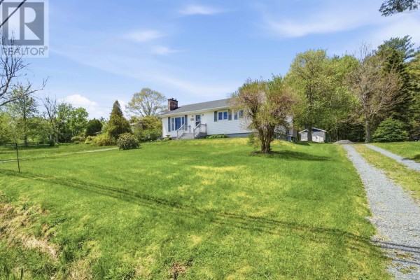 Wide exterior view of a white ranch house on a grassy lot with trees and a driveway. - 512 Windsor Junction Road, Windsor Junction