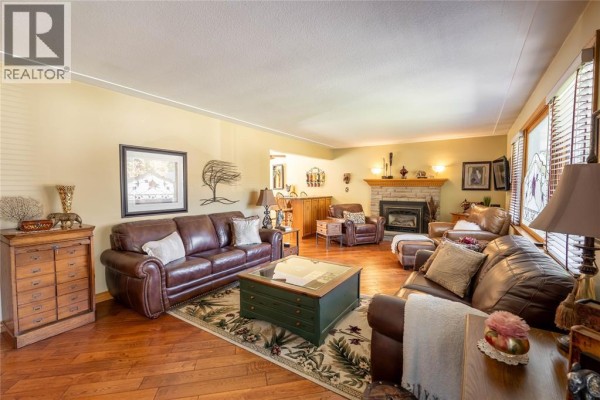 Living room with leather sofas, fireplace, hardwood floors, and a patterned rug. - 512 Zone Street, Plympton Wyoming