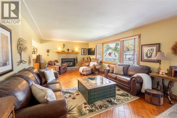 Living room showcasing leather furniture, fireplace with stone surround, and large windows. - 512 Zone Street, Plympton Wyoming