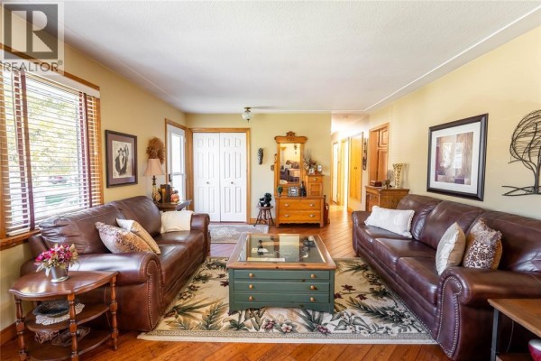 Spacious living room with two leather sofas, hardwood floors, and a view of the hallway. - 512 Zone Street, Plympton Wyoming