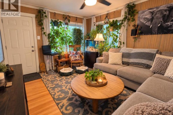 Living room with a sectional sofa, houseplants, aquarium, and a door leading outside. - 5122 45 Avenue, Spirit River