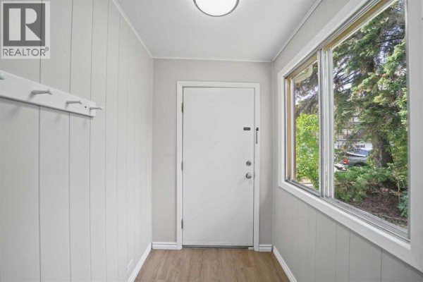 Entranceway with pale gray paneled walls, a white door, and a large window. - 5122 49 Street, Olds