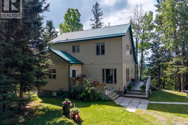 Rear view of the beige house with a lower level walkout and a paved patio. - 5123 Township Road 342 A, Rural Mountain View County