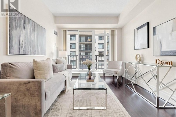 A kitchen island with granite countertops, dark wood cabinetry, and stainless steel appliances, overlooking a living area. - 513 - 131 Upper Duke Crescent, Markham