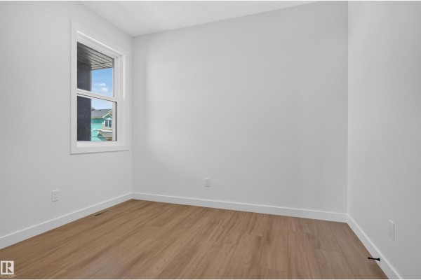 Empty room with white walls, a window, and light wood laminate flooring. - 5130 Cawsey Bn Sw, Edmonton