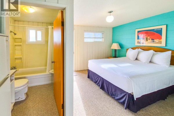Bedroom with a king-size bed and a door opening to a bathroom with a bathtub. - 5133 7th Avenue, Okanagan Falls
