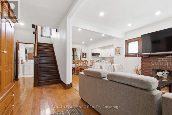 Interior view showing a staircase, living room, and kitchen area with dining table. - 5134 Victoria Avenue E, Niagara Falls