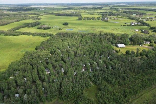 Aerial view of a wooded property with a lake in the background at sunset. - 51380a Rge Road 205, Rural Strathcona County
