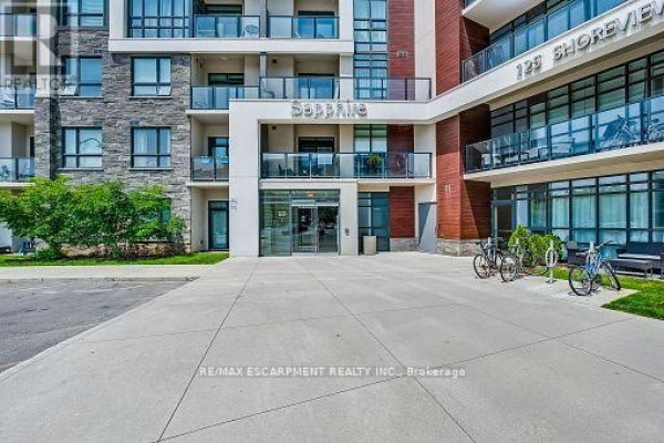 Entrance to the Sapphire building with glass doors, bicycles, and concrete plaza. - 514 - 125 Shoreview Place, Hamilton