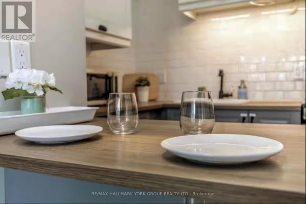 Kitchen counter with two plates, two glasses, and flower arrangement, showing white subway tile backsplash. - 514 - 796468 19 Grey Road, Blue Mountains