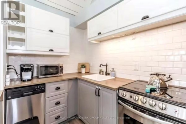 Compact kitchen with light grey and white cabinetry, stainless steel appliances, and tile backsplash. - 514 - 796468 19 Grey Road, Blue Mountains