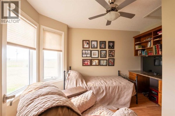 Cozy bedroom with a bed, wall of photos, and a ceiling fan. - 514 6a Street N, Champion