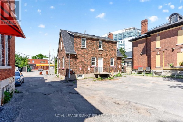 Rear view of the brick building showing a white door, windows and surrounding asphalt. - 514 Princess Street, Kingston