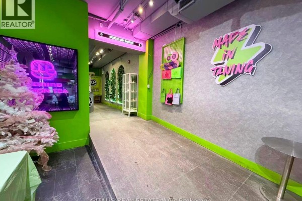 Commercial space interior with large screen, pink Christmas tree, and hanging bags. - 514 Yonge Street, Toronto