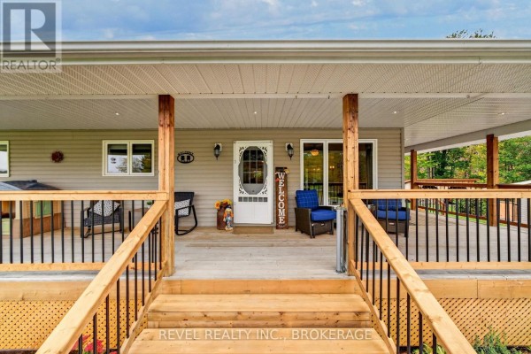 View of the front porch entrance with wooden stairs, railings, and seating. - 5140 Arena Boundary Road, Frontenac