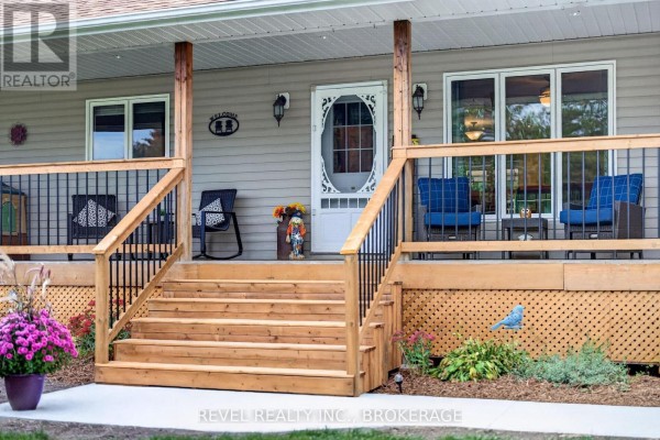 Close-up of the front porch steps and entrance to the beige house with furniture. - 5140 Arena Boundary Road, Frontenac