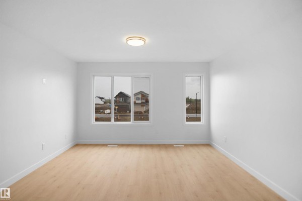 Open living area with hardwood flooring, large windows, and chandelier - 5143 River's Edge Wy Nw, Edmonton