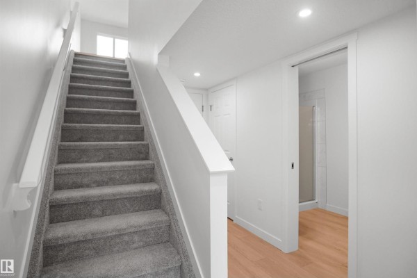 Landing area with doors to rooms, carpeted floors, and mirrored closet - 5145 River's Edge Wy Nw, Edmonton