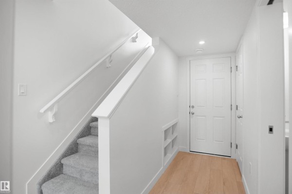 Kitchen area with white cabinetry, sink, and access to outdoor space - 5145 River's Edge Wy Nw, Edmonton