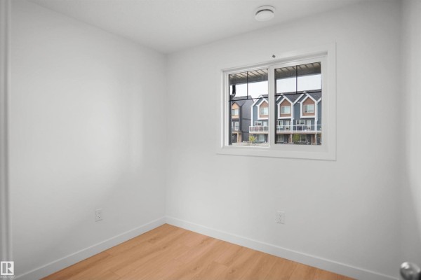 Spacious living room with large windows, light wood flooring, and neutral walls - 5145 River's Edge Wy Nw, Edmonton