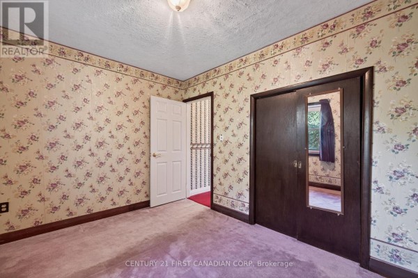 Floral wallpaper, pink carpet, and mirrored closet in a bedroom - 5147 Egremont Drive Middlesex Centre