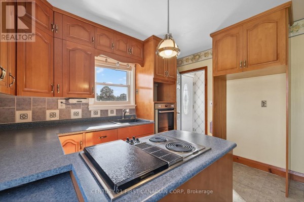 Kitchen with wooden cabinets, island cooktop, oven and sink - 5147 Egremont Drive Middlesex Centre