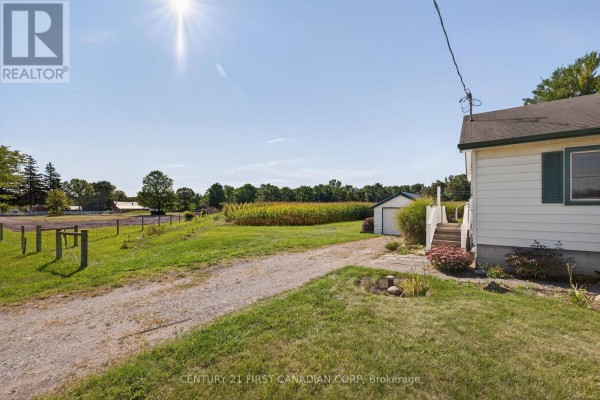 White house with green shutters, corn field, detached garage, and fence - 5147 Egremont Drive Middlesex Centre