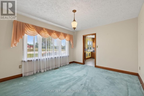 Living room with teal carpet and bay window overlooking fields - 5147 Egremont Drive Middlesex Centre