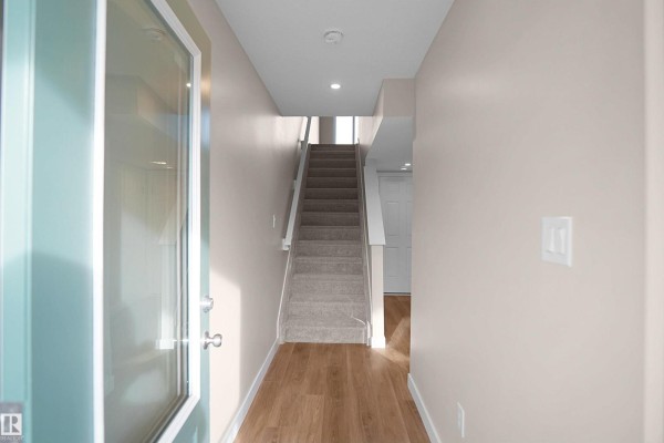 Hallway with two open doors, one leading to a closet and the other to stairs - 5147 River's Edge Wy Nw, Edmonton