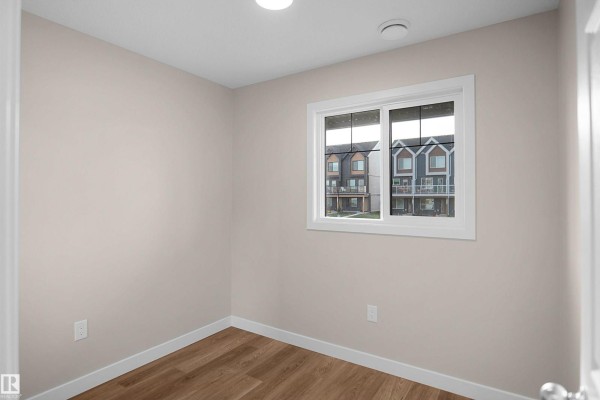 Spacious living area with light wood flooring, chandelier, and open layout to kitchen - 5147 River's Edge Wy Nw, Edmonton