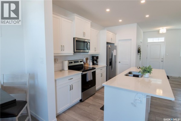 Kitchen view showing white cabinetry, stainless steel appliances, and an island. - 5148 Buckingham Drive E, Regina