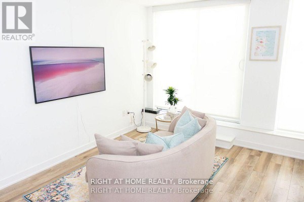 A living room with a pink sofa, large windows, and abstract art on the wall. - 515 - 106 Dovercourt Road, Toronto