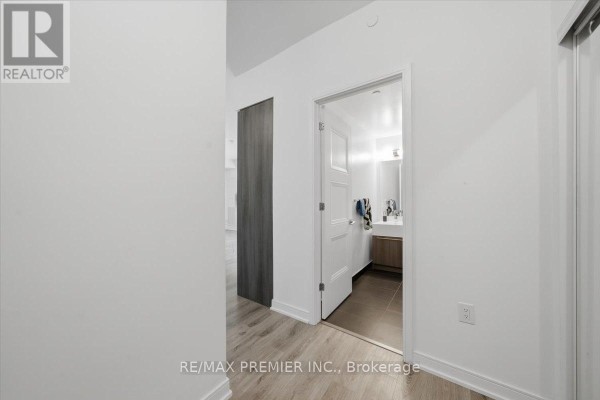Interior hallway view showing an open bathroom door with a vanity and tiled floor. - 515 - 25 Neighbourhood Lane, Toronto