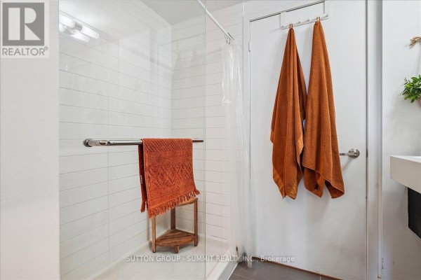 White tiled shower with orange towels and wooden shelf - 515 - 38 Dan Leckie Way Toronto