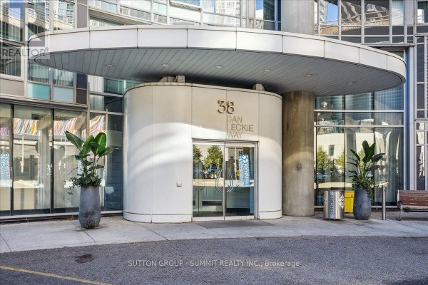 Modern building entrance at 38 Dan Leckie Way with glass doors, planters, and signage - 515 - 38 Dan Leckie Way Toronto