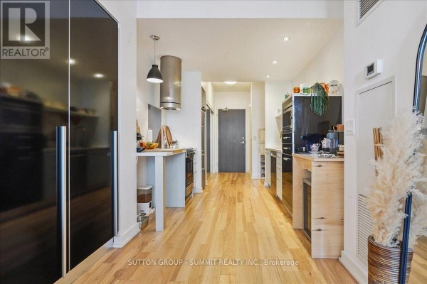 Modern galley kitchen with hardwood floors and stainless steel range hood - 515 - 38 Dan Leckie Way Toronto