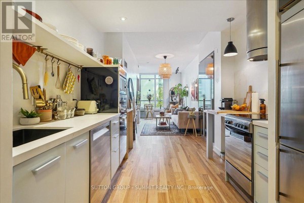Modern kitchen with stainless steel appliances and island, leading to living area. 515 - 38 Dan Leckie Way Toronto