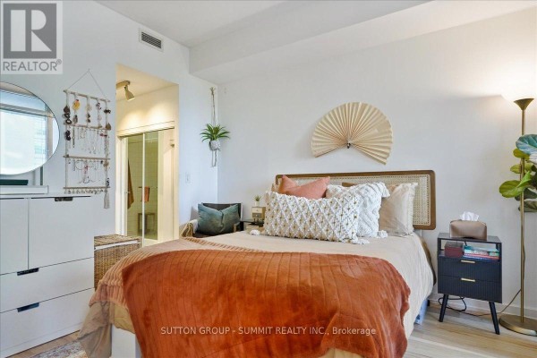 Bedroom with rattan headboard, decorative fan art, and ensuite bathroom access - 515 - 38 Dan Leckie Way Toronto