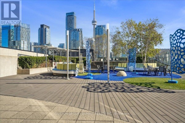 Modern rooftop terrace with seating, tables, sculptures, and CN Tower view - 515 - 38 Dan Leckie Way Toronto