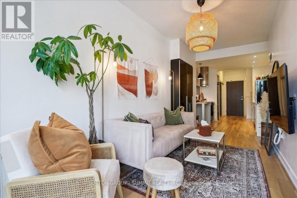 Pink sofa and rattan chairs in a modern living room with an open kitchen. - 515 - 38 Dan Leckie Way Toronto