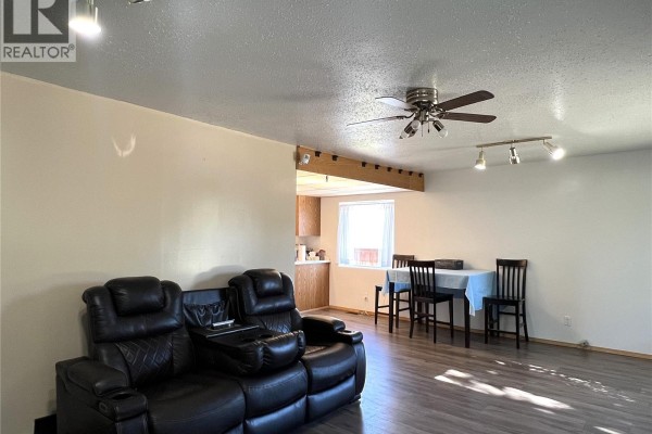 Living room with a sectional sofa facing a dining area and kitchen entrance. - 515 3rd Avenue W, Meadow Lake