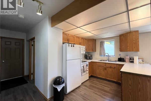 Kitchen with wooden cabinets, white appliances, and a sink area. - 515 3rd Avenue W, Meadow Lake