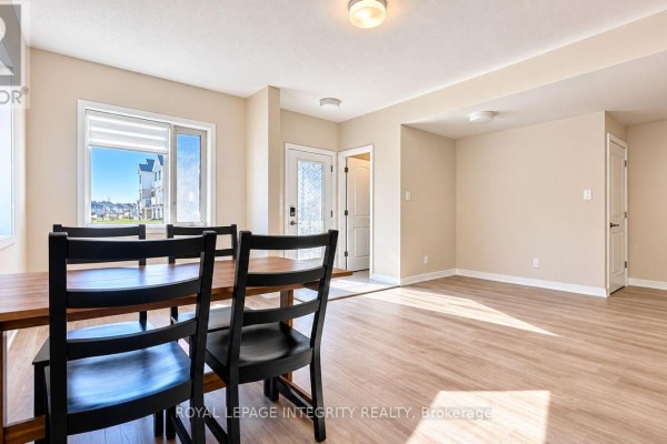 Open concept living area with light wood floors, a white kitchen, stainless steel appliances, and a breakfast bar. - 515 Celestine Private, Ottawa