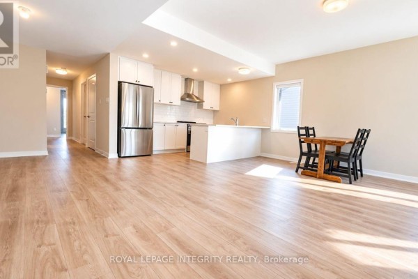 Open concept living area with light wood floors, a white kitchen, stainless steel appliances, and a breakfast bar. - 515 Celestine Private, Ottawa