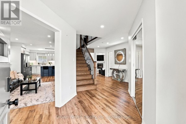 Foyer with hardwood floors, staircase, and an open view to the living room and kitchen. - 515 Ormond Drive, Oshawa