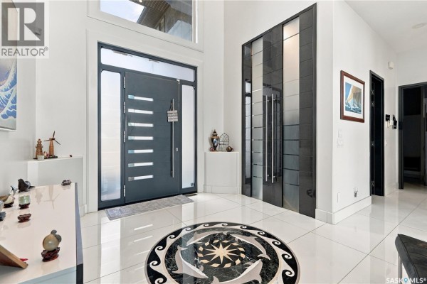 Entryway with a contemporary door, large tiled floor, and decorative inlaid circular mosaic. - 515 Pohorecky Lane, Saskatoon