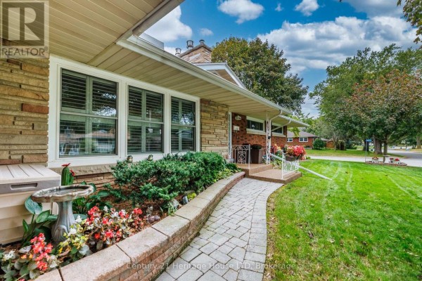 Stone pathway leads to the front entrance of a brick house with well-maintained landscaping. - 5159 Shirley Avenue, Niagara Falls